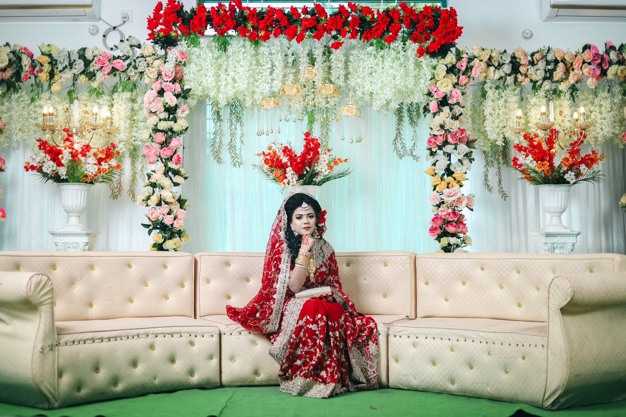 Stunning Indian bride in red attire amidst lavish floral decorations